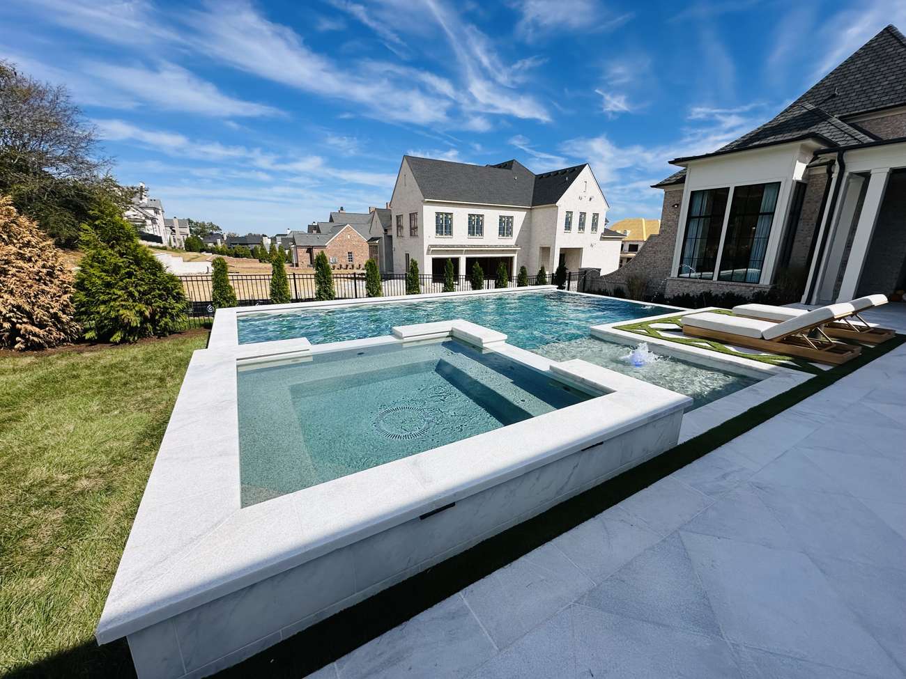 Raised spa spilling over into a backyard pool